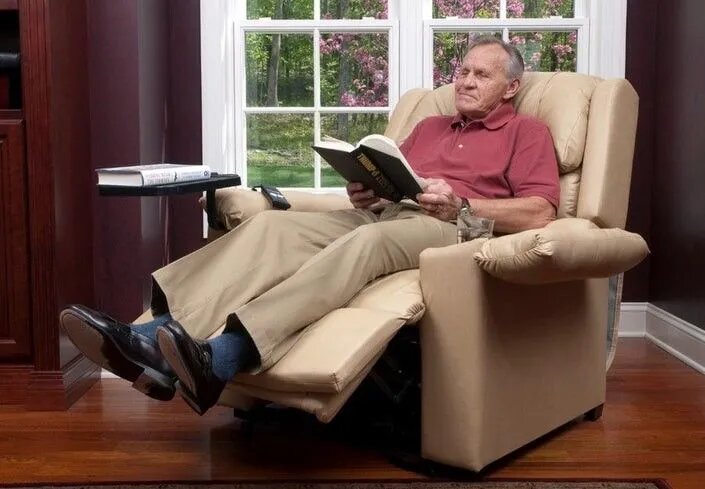 old man relaxing on electric recliner reading a book
